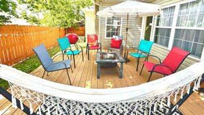 Een terras met een hangmat, een barbecue en tuinmeubilair.
