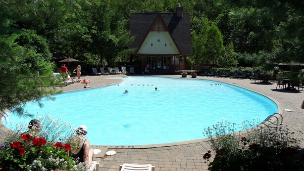 Ein Pool, umgeben von Liegestühlen und einem Gebäude mit einem Dreiecksdach.