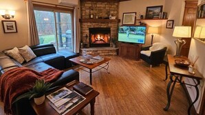 Ein gemütliches Wohnzimmer mit Kamin, Fernseher und bequemen Sitzmöglichkeiten.