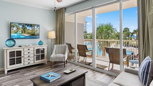 A hotel room with a balcony, a ceiling fan, a TV, a dining table, and a sofa. - Gulfside 215 ~ Ocean Views ~ Beach Service ~ Destin West! (Fort Walton Beach)