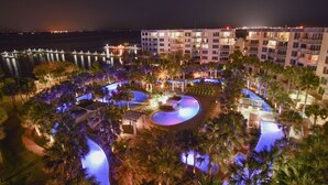 A resort with a large swimming pool, palm trees, and a view of the ocean at night. - Gulfside 215 ~ Ocean Views ~ Beach Service ~ Destin West! (Fort Walton Beach)