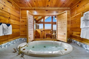 Een houten chalet met een hottub, houten wanden en uitzicht op een terras en bergen.