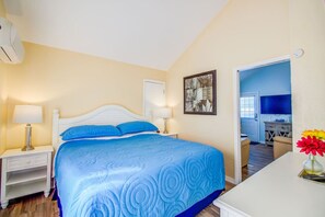 A bedroom with a bed, two bedside tables with lamps, a painting on the wall, and a view into the kitchen. - Near beach. Daily rentals. Villa 1, Pool. King bed (Sarasota)