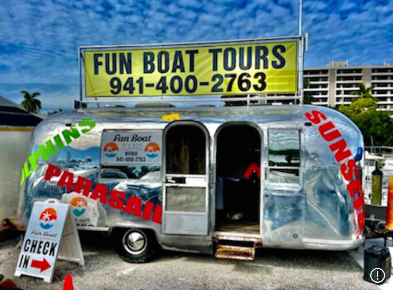 A mobile food truck with a sign advertising Fun Boat Tours and a phone number.