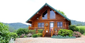 A log cabin with a steeply pitched roof, large windows, and a front porch with a staircase. - ROMANTIC LOG CABIN OPEN FOR BUSINESS MT.VIEWS, 2/1,10 MIN AVL, FP,WiFi, FIREPIT (Leicester)