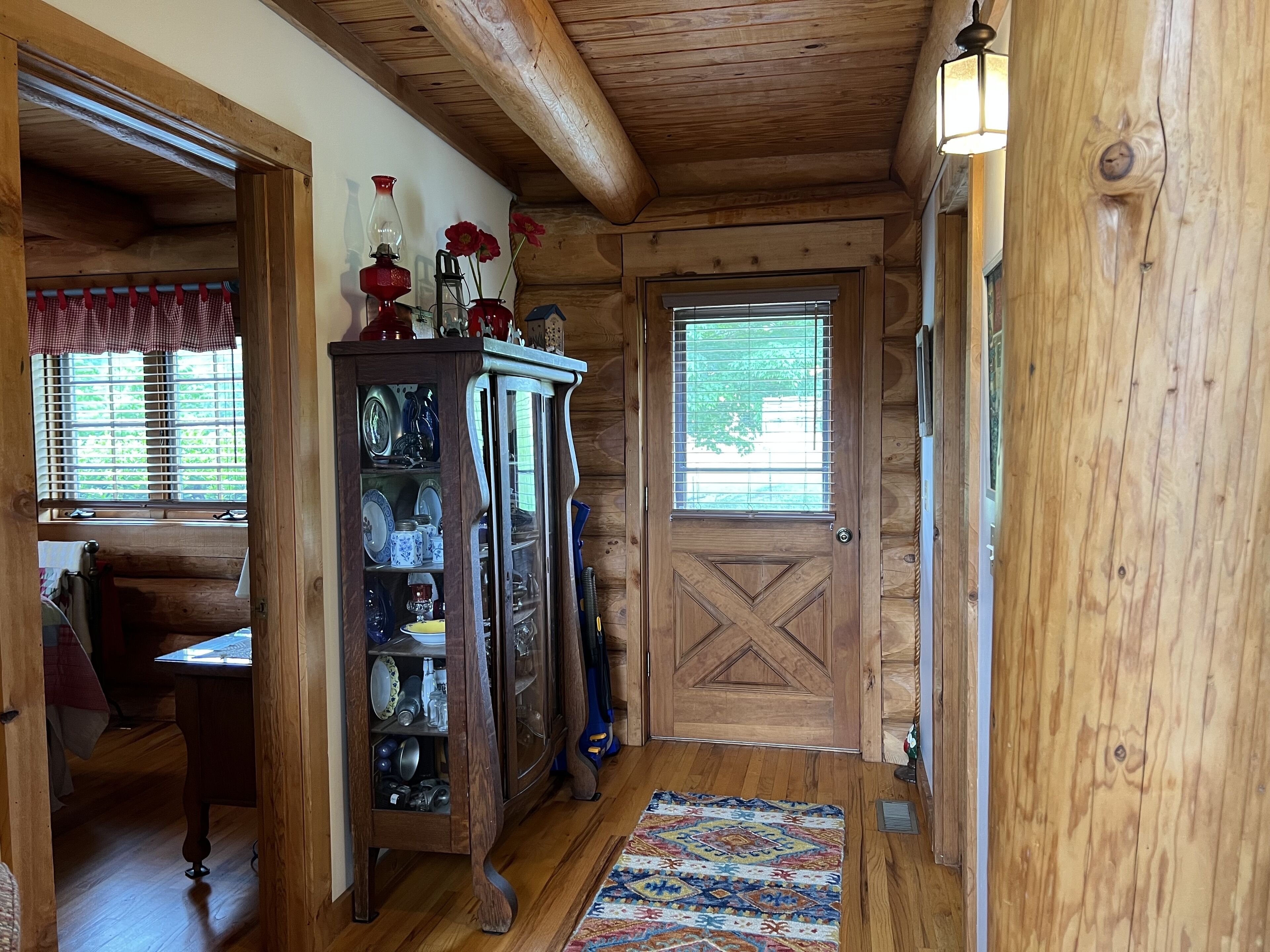 Un intérieur en bois avec une vitrine, un tapis à motifs et une porte dotée d’une fenêtre.
