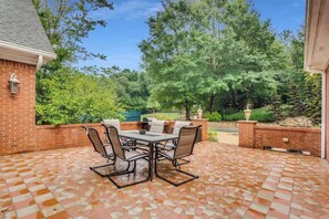 A patio with a tiled floor, a table with chairs, and a brick wall. - Conyers pool estate, sleeps 12 (Conyers)