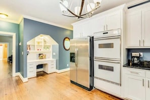 Una cocina con armarios blancos, un refrigerador de acero inoxidable y un horno empotrado.