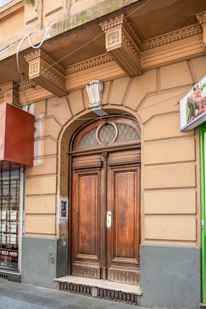 Una gran puerta doble de madera con tallas elaboradas y una pequeña ventana en la parte superior.