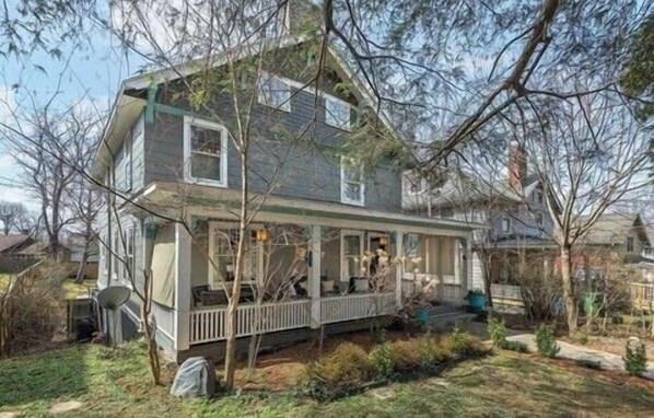 A two-story house with a porch, surrounded by trees and a garden. -  Historic Montford house - Walk to downtown Sleeps 6 (Asheville)