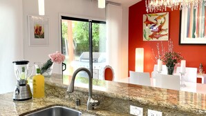 Eine moderne Küche mit Granit-Arbeitsplatten, Edelstahl-Spülen, einem eingebauten Backofen und einer roten Akzentwand.