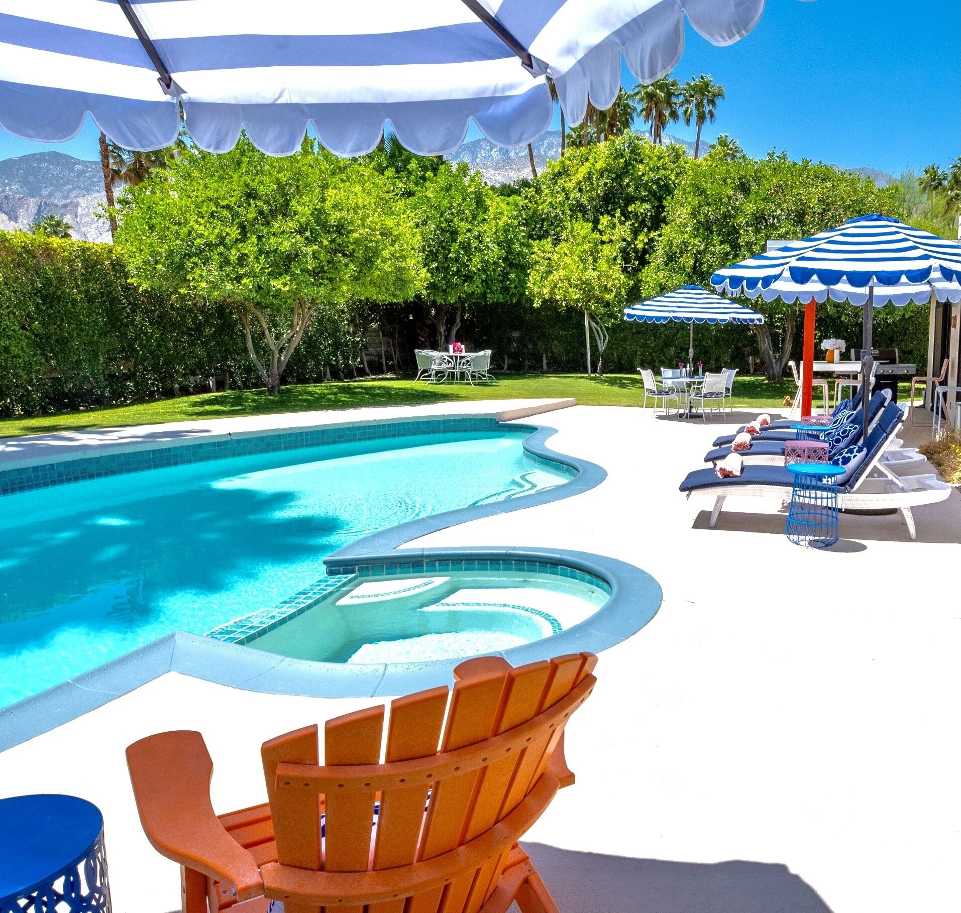 A swimming pool with a sunken area, surrounded by lounge chairs and umbrellas.