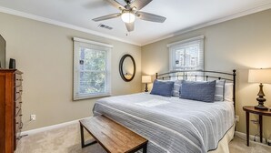 A bedroom with a bed, a ceiling fan, two bedside tables with lamps, a bench, and a dresser. - Pet Friendly Home w/ Screened Porch & Pool (Hilton Head Island)