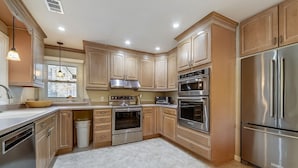 A modern kitchen with stainless steel appliances, wooden cabinets, and a large refrigerator. - Pet Friendly Home w/ Screened Porch & Pool (Hilton Head Island)