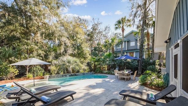 A backyard with a swimming pool, lounge chairs, and a dining area. - Pet Friendly Home w/ Screened Porch & Pool (Hilton Head Island)