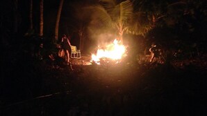 A campfire with a chair and a person standing nearby in a forested area. - Paradise! Beach Rental with Private Pool!! (Esterillos Oeste)