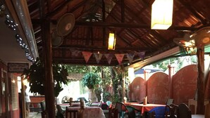 An indoor dining area with wooden tables and chairs, a tiled floor, and a thatched roof. - Paradise! Beach Rental with Private Pool!! (Esterillos Oeste)