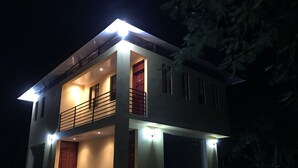 A modern two-story house with a balcony, a garage, and a well-lit entrance. - Paradise! Beach Rental with Private Pool!! (Esterillos Oeste)
