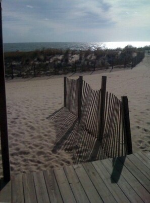 A wooden deck leading to a sandy beach with a view of the ocean and dunes in the background. - 4 Bedroom 2 1/2 Bath Ocean Front Townhouse with Outdoor Pool (Ocean City)