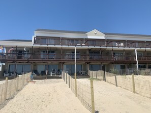A beachfront hotel with multiple balconies, outdoor seating, and a sandy beach area. - 4 Bedroom 2 1/2 Bath Ocean Front Townhouse with Outdoor Pool (Ocean City)