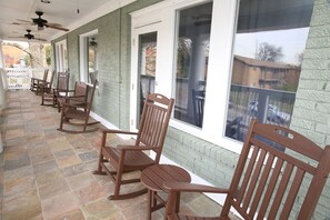 Huge outdoor porch with rocking chairs, tables and a bench. 