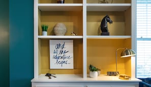 Cozy space with a shelving unit, framed sign, and modern lamp.