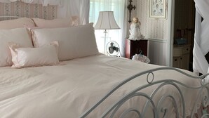 A bedroom with a canopy bed, a bedside table with a lamp, and a dresser. - Charming Victorian-Style Guest House (Cody)