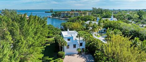 A coastal property with a central white building, surrounded by lush greenery and a marina.