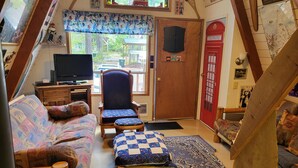 Acogedor dormitorio en ático con sofá, sillón, mesita y televisor.