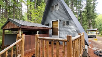 Uma cabana com um deck de madeira, um pequeno alpendre e uma área cercada.