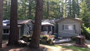 A mobile home with a deck, surrounded by trees. - The Perfect Cottage For A Family Vacation At The Lake (Cultus Lake)