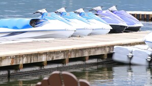 A row of jet skis docked at a pier with a forested hill in the background. - The Perfect Cottage For A Family Vacation At The Lake (Cultus Lake)