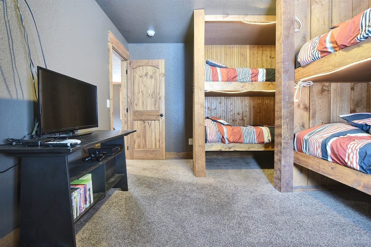 A room with bunk beds, a TV, and a wooden door.