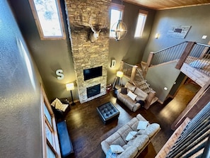A spacious living area with a stone fireplace, a sofa, a coffee table, and a staircase. - Eagle View Lodge at Terry Peak (Lead)