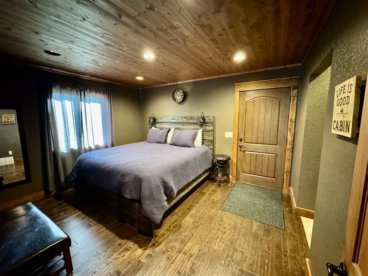 A bedroom with a bed, a wooden door, a clock, and a sign on the wall.