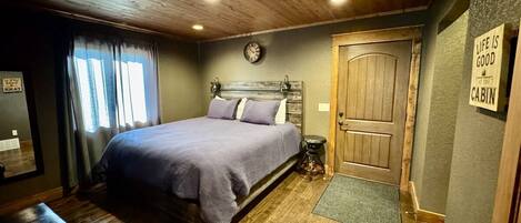 A bedroom with a bed, a wooden door, a clock, and a sign on the wall.