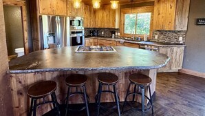 Una cocina con armarios de madera, una isla central con taburetes y un salpicadero de piedra.