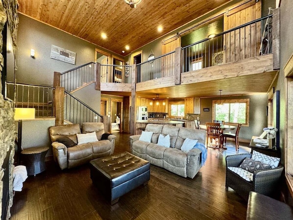 A spacious living area with a high ceiling, a staircase, and a kitchen area. - Eagle View Lodge at Terry Peak (Lead)