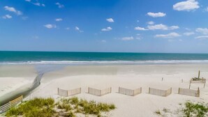 Een strand met een houten omheining, een bankje en een klein gebouwtje.