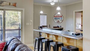 Uma cozinha com área de bar, banquetas, luminárias pendentes e um letreiro com a palavra 'café' na parede.