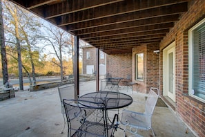 Relax in a shaded patio area with metal tables and chairs, adjacent to a brick building with large windows.