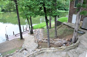 Une terrasse au bord du lac, avec des marches en pierre, une plateforme en bois et un muret de soutènement en pierre.