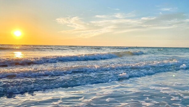 A beach scene with waves and a sunset. - Live like a local. Heated Pool, steps to the Beach. 2nd floor unit. Unit B (Indian Rocks Beach)