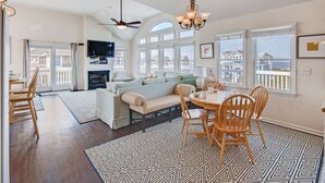 A spacious living area with a dining table, chairs, a sofa, and a fireplace. - Semi-Soundfront Dog Friendly w/ Pool, Hot Tub, Game Room, Community Boat Ramp (Salvo)