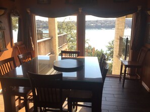 Enjoy meals with a view of the water and hilly landscape from this dining area with a glass table and comfortable seating.