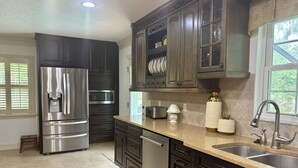 Una cocina moderna con armarios oscuros, electrodomésticos de acero inoxidable y encimera de granito.