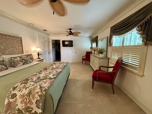 A bedroom with a bed, a desk, a chair, a ceiling fan, a TV, and a window with blinds. - Casa Del Rio-LAST MINUTE DISCOUNT FOR AUGUST Waterfront-Pool-Dock-Kayaks-Pets (Crystal River)