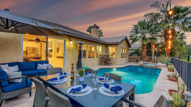 A backyard with a pool, dining area, and outdoor seating.