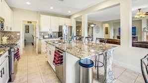 A spacious kitchen with granite countertops, stainless steel appliances, and a large island with bar stools.