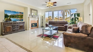 A spacious living room with a large flat-screen TV, a fireplace, a sofa, and a coffee table.